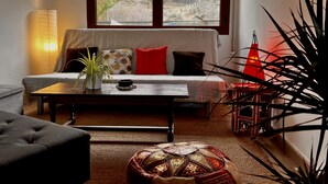 A cozy living room with a sofa, a coffee table, a potted plant, and a red lamp. - Casa Rural Hitohouse Bed&climb (Albarracín)