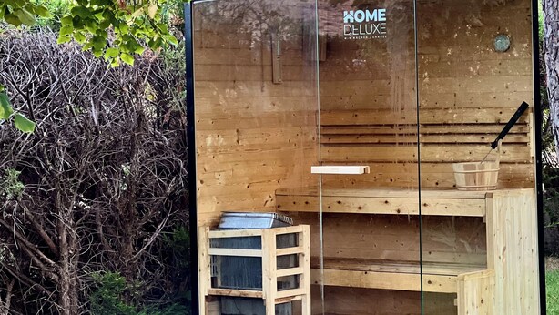 A wooden cabin with a glass door, labeled "KOME DELUXE," featuring a wooden bench and a small table. - Casa Rural Hitohouse Bed&climb (Albarracín)