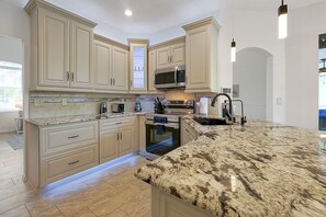 A kitchen with beige cabinetry, a granite countertop, a stainless steel oven, and a microwave. - Southern Dunes: pool/spa; air hockey/game room (Haines City)