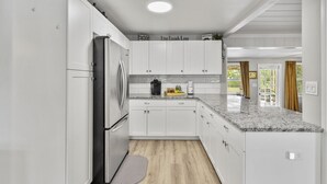Eine moderne Küche mit weißen Schränken, einer Arbeitsplatte aus Granit und einem Edelstahl-Kühlschrank.