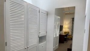 A hallway with a white wardrobe, a desk with a lamp, and a chair. - The Blossoms (Diyathalawa)