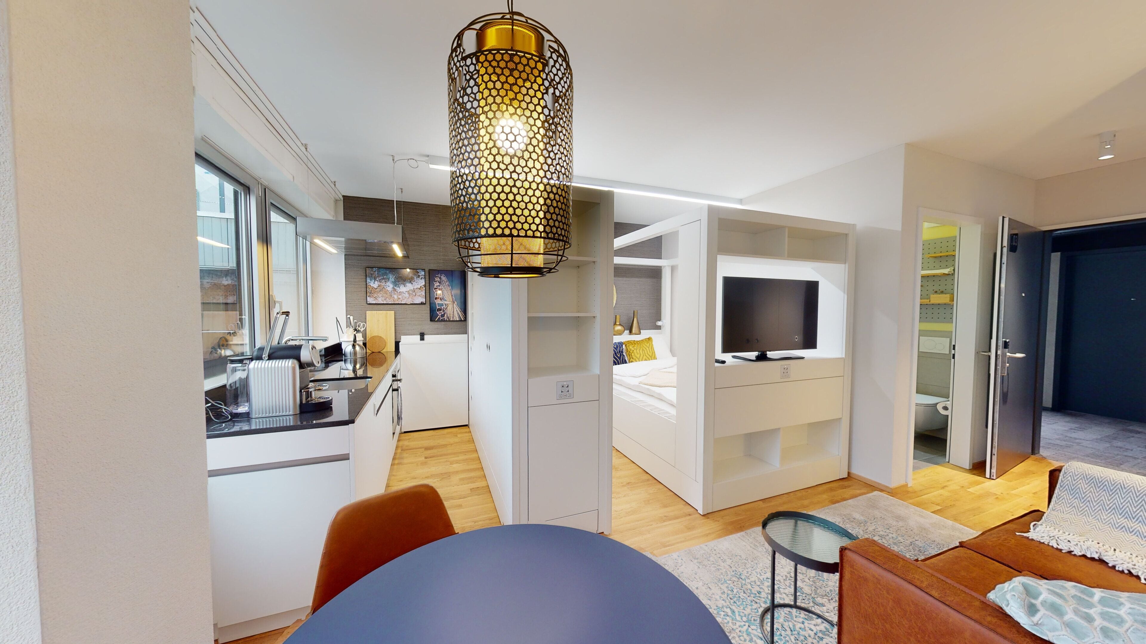 Een modern appartement met een keuken, eethoek en woonkamer. Het heeft een groot raam, een eettafel, een bank en een televisie.
