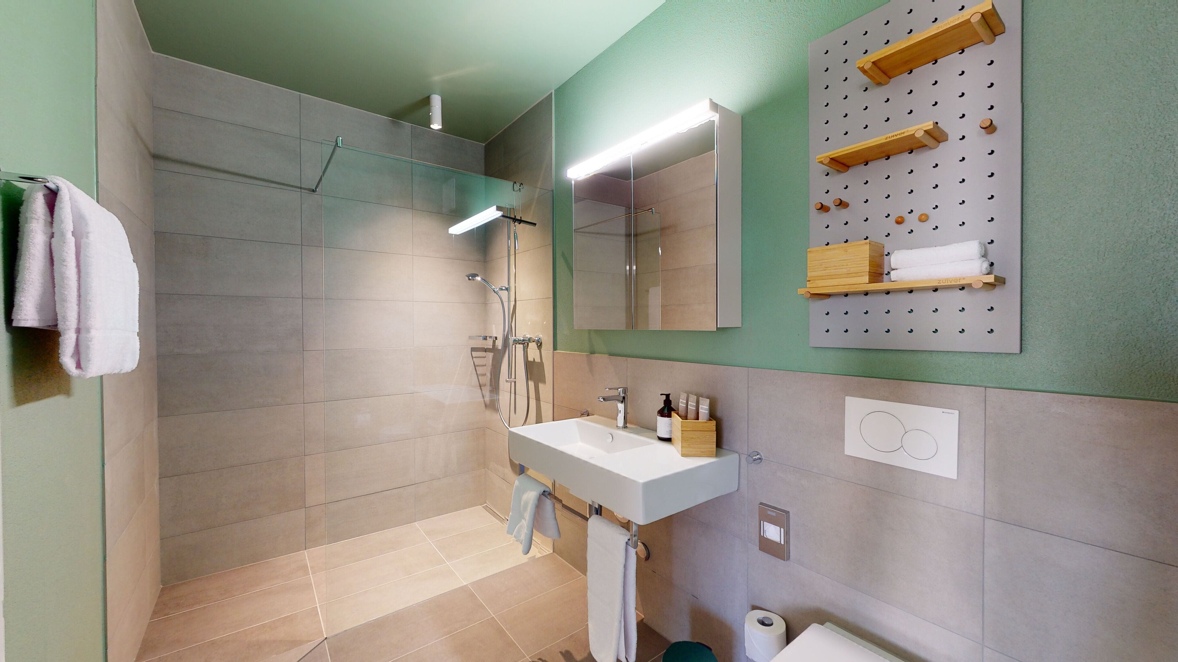 A modern bathroom with a shower, sink, and storage wall.