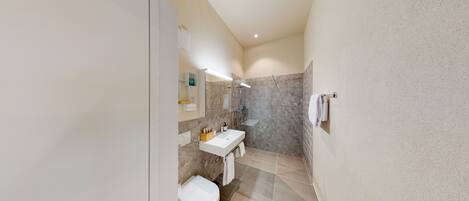 A modern bathroom with a shower, toilet, and sink.