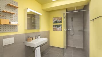 A modern bathroom with a large mirror, a sink, and a shower.