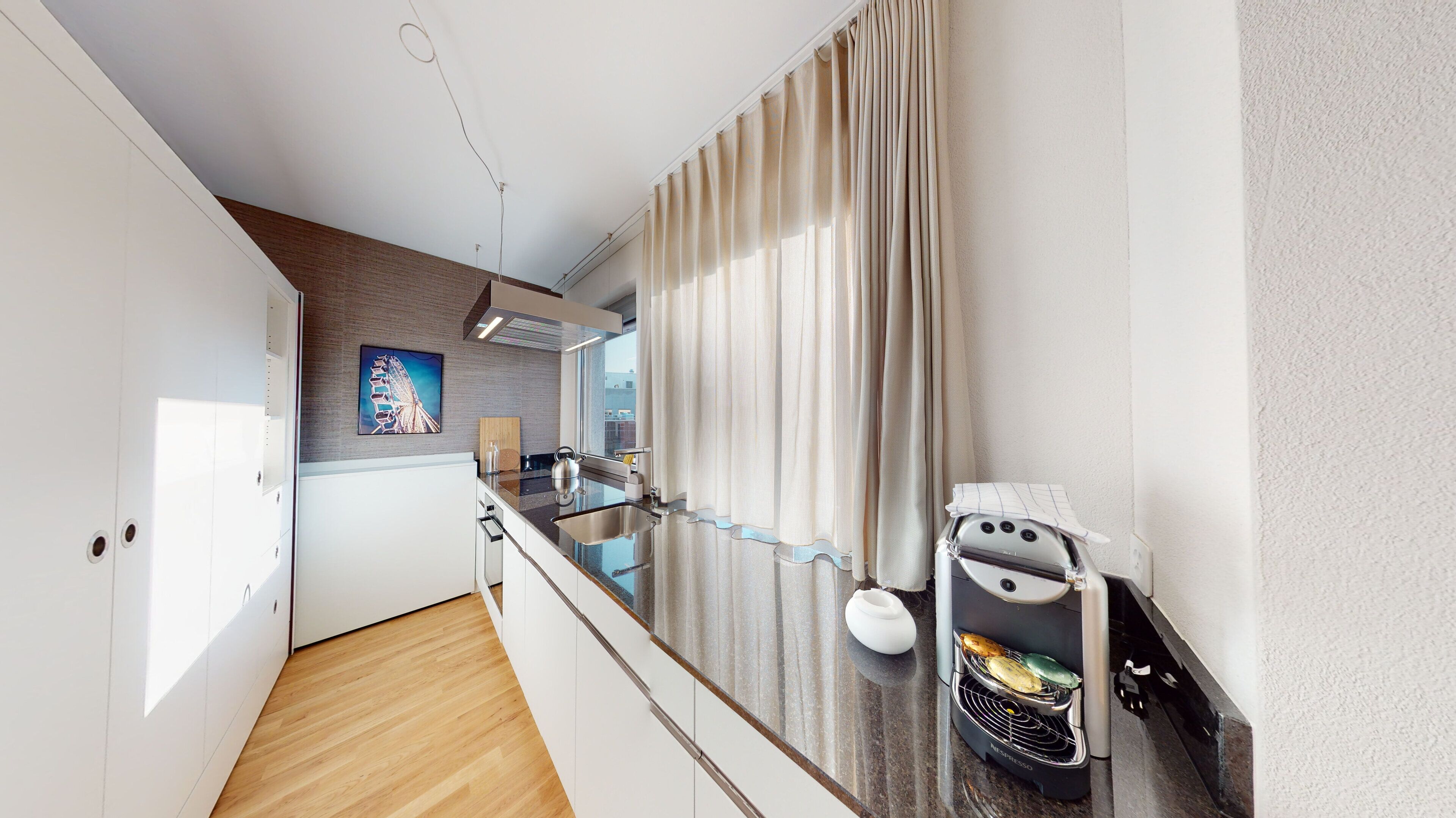 A modern kitchen with a built-in espresso machine, a wooden cutting board, and a stainless steel sink.