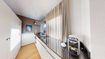 A modern kitchen with a built-in espresso machine, a wooden cutting board, and a stainless steel sink.