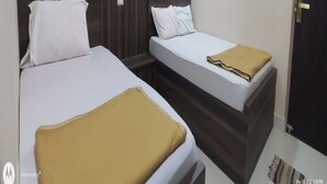 A hotel room with two beds, each with a wooden headboard and white bedding. - Sri Sivalakshmi AC Guest House (Vriddhachalam)