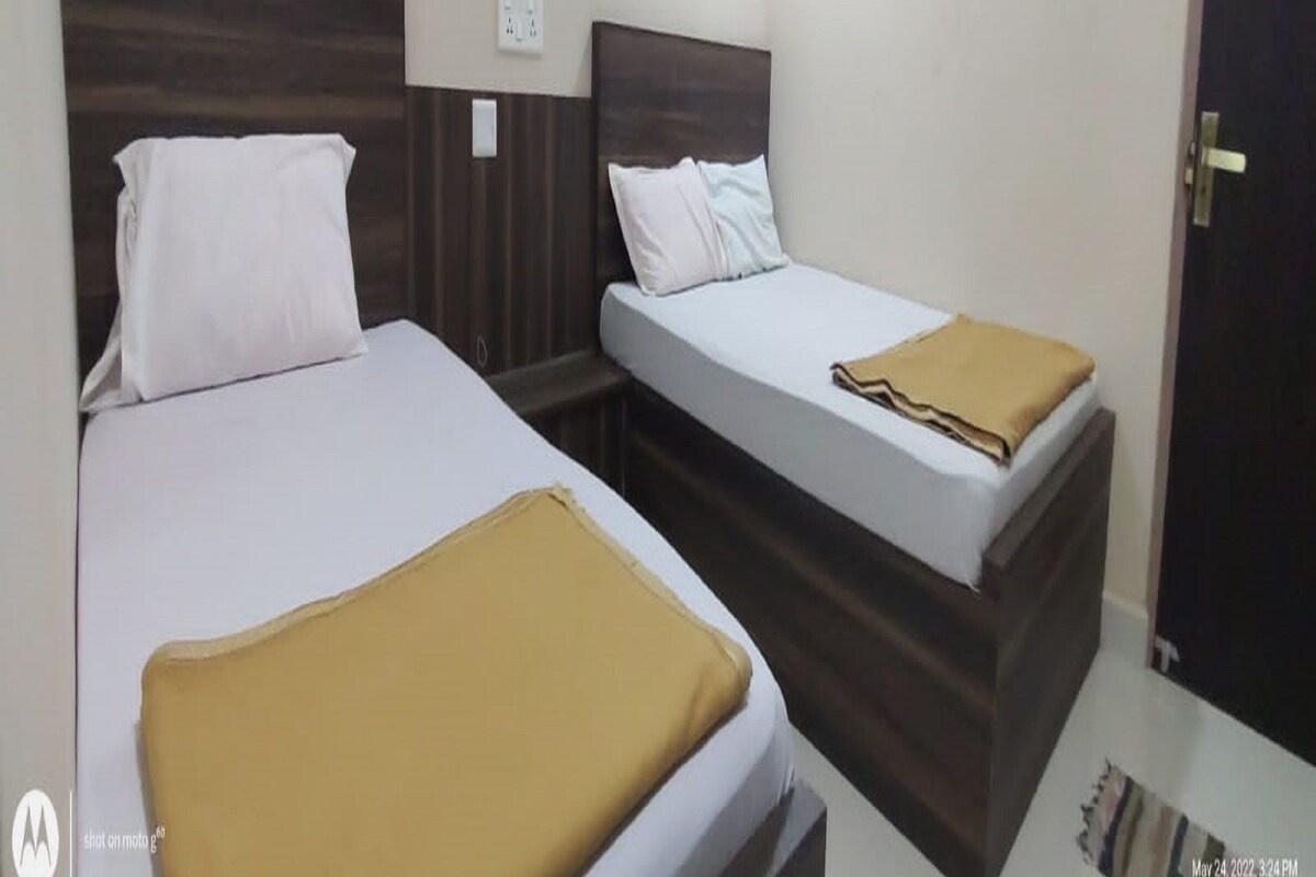 A hotel room with two beds, each with a wooden headboard and white bedding.