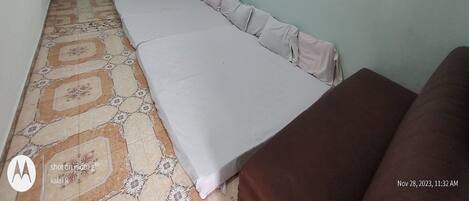 Quarto com cama grande, ventilador de teto, ar condicionado e televisão fixada na parede.