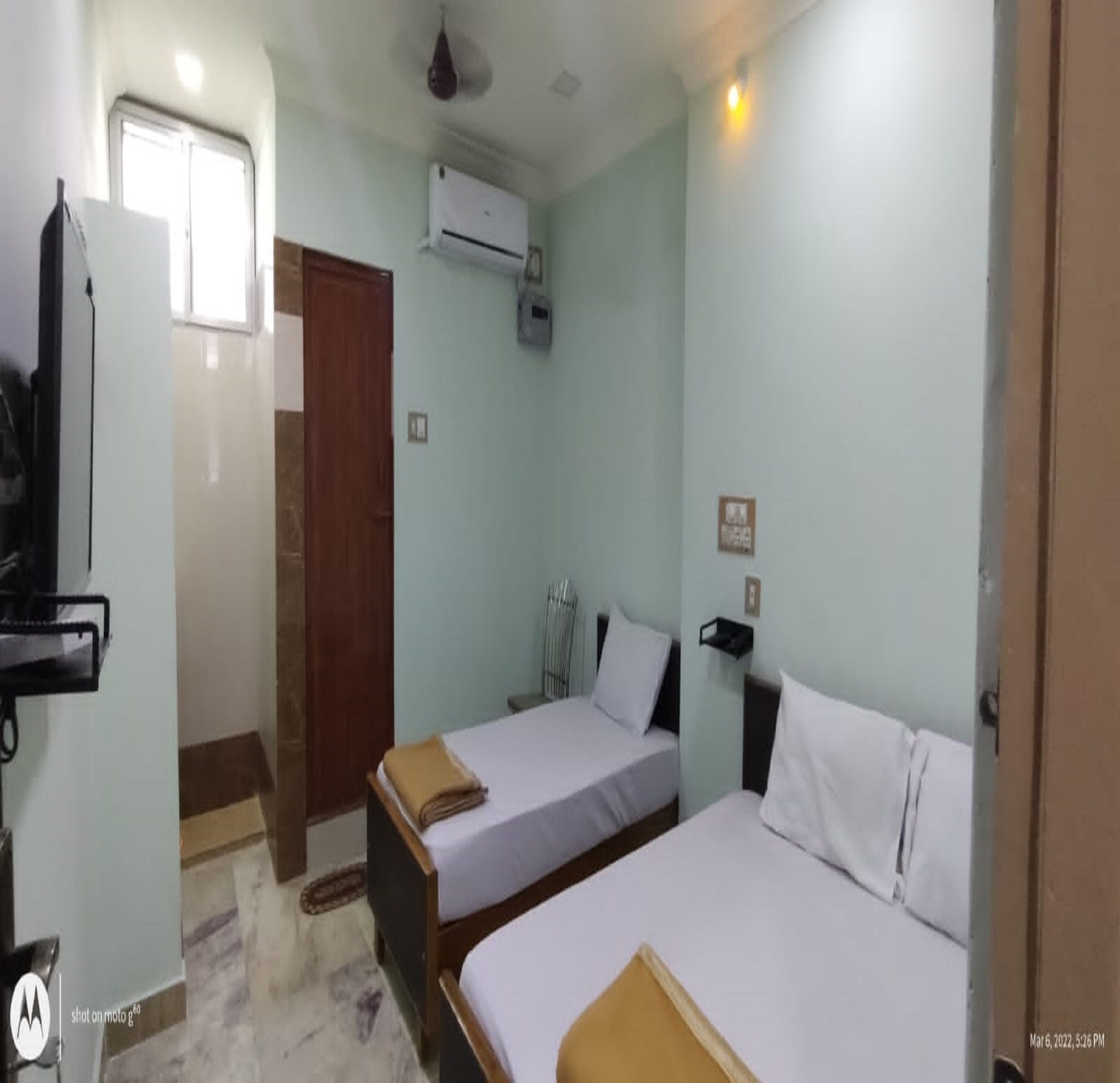 Een hotelkamer met twee bedden, een kledingkast, een airconditioner en een televisie.