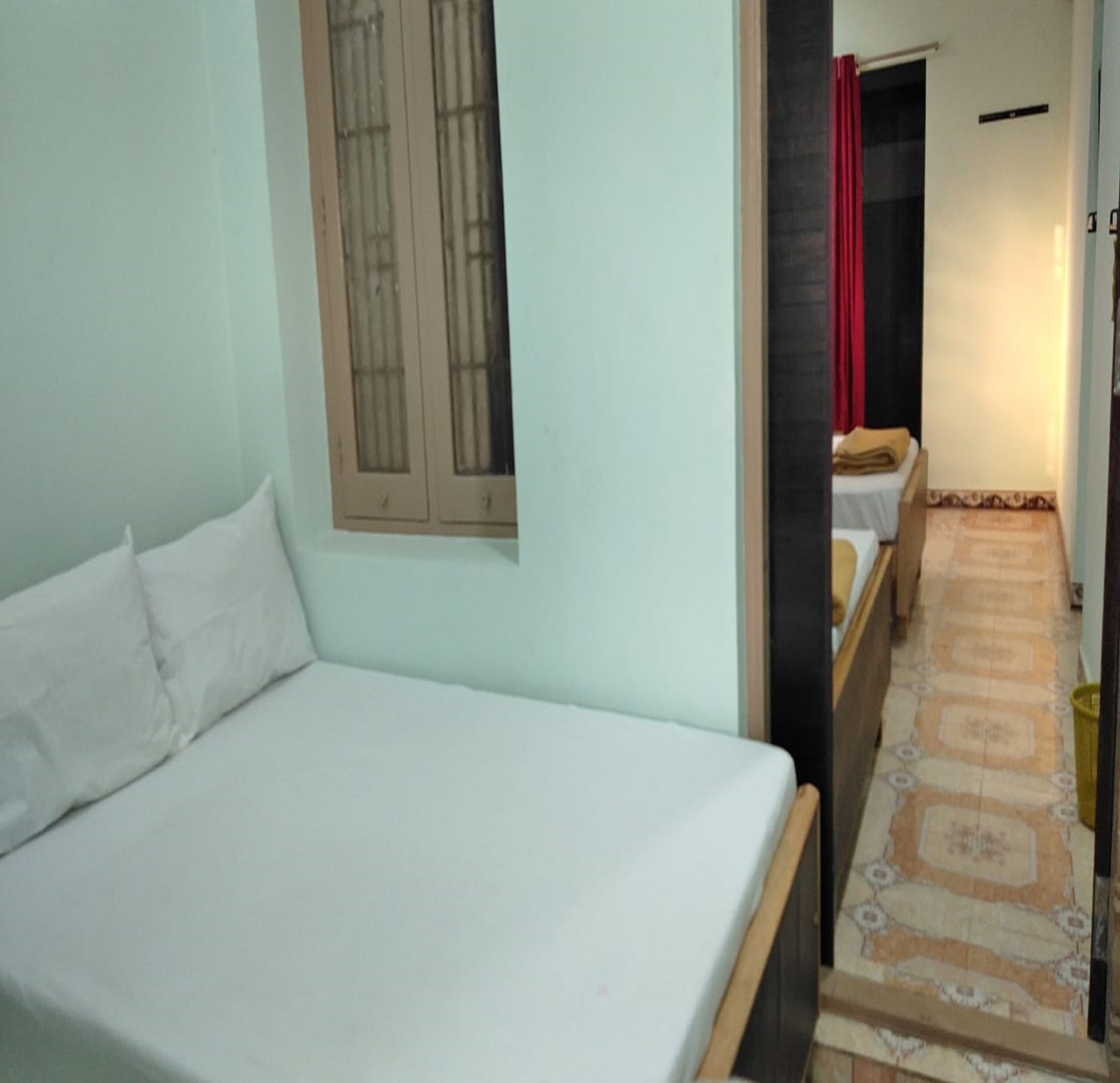 A room with a bed, a window with bars, a door leading to another room, and a patterned floor.