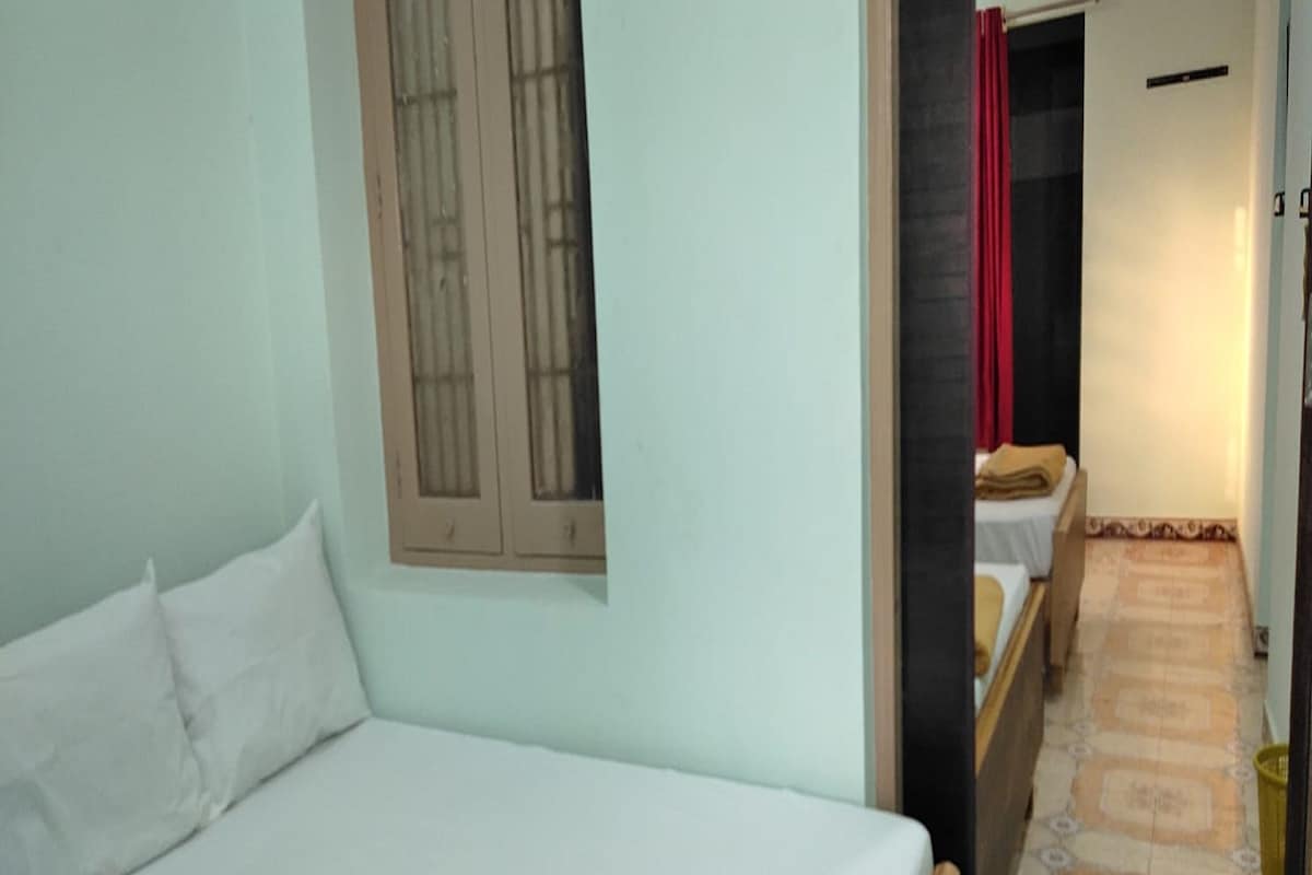 A room with a bed, a window with bars, a door leading to another room, and a patterned floor.