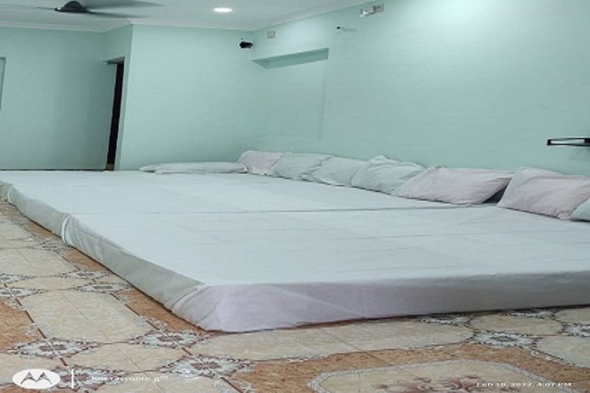 A bedroom with a large bed, two ceiling fans, and a patterned rug.