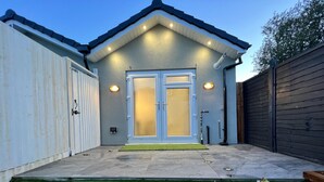 A modern house with a two-car garage, a front door with glass panels, and a small front yard with artificial grass. - Stunning 1-bed Studio in Greenford (Greenford)