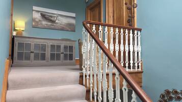A staircase with white balusters and a wooden handrail leading to a door with a basket on the wall.