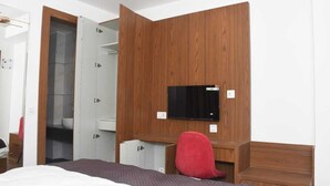 A bedroom with a bed, a desk, a chair, a TV, and a wardrobe. - SWARN BHOOMI (Kanpur)