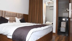 A bedroom with a bed, a wooden headboard, a brown curtain, a bathroom with a toilet and sink, and a mirror. - SWARN BHOOMI (Kanpur)