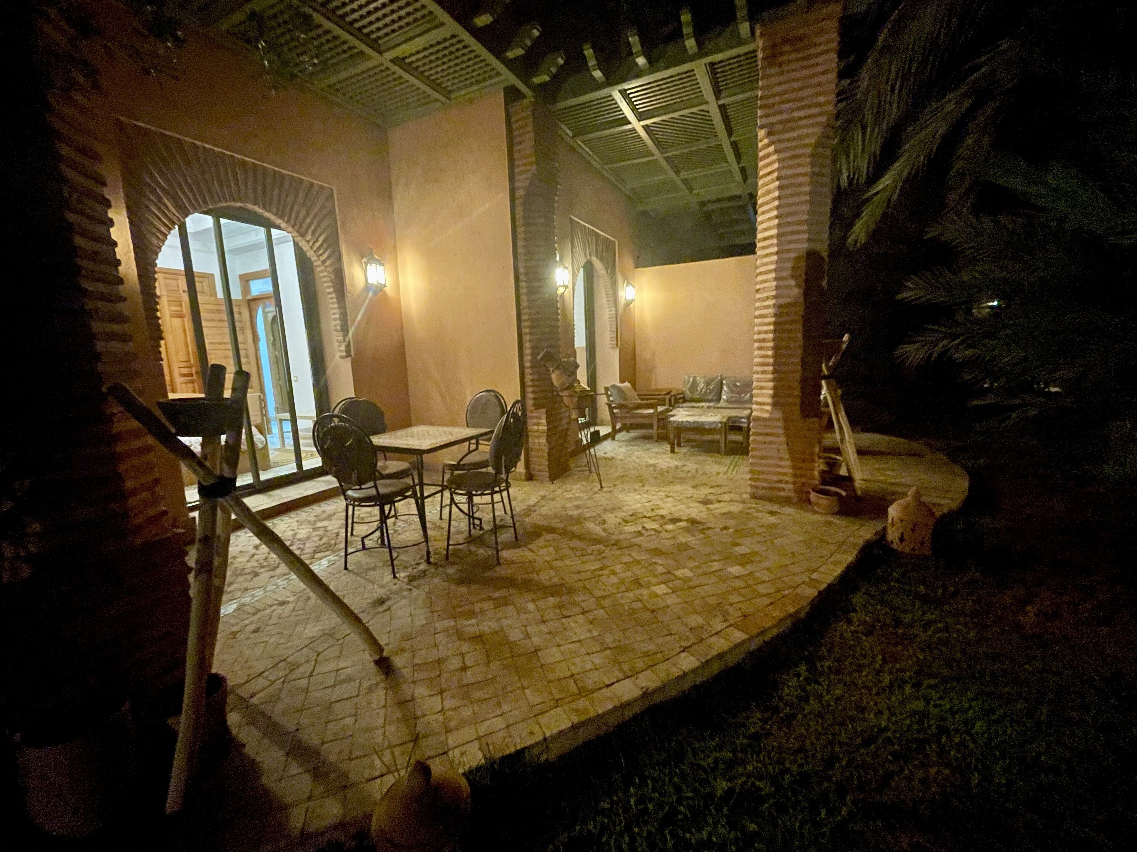 An outdoor patio area with stone flooring, a table with chairs, and a wooden bench.