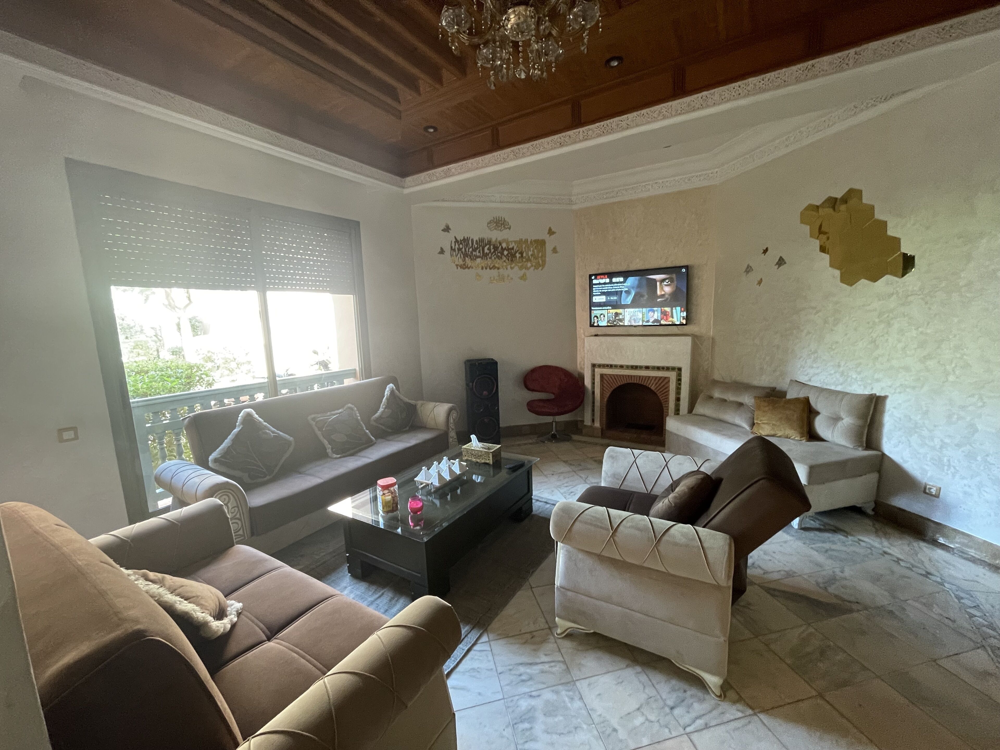 A living room with a sofa, armchairs, a coffee table, a TV, and a fireplace.