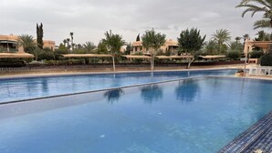 A large, clear swimming pool with a tiled edge, surrounded by palm trees and a fence. - Au Riad De La Palmeraie - Marrakech  (Marrakech)