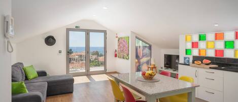 A modern apartment with a dining area, kitchen, and a balcony with a city view.