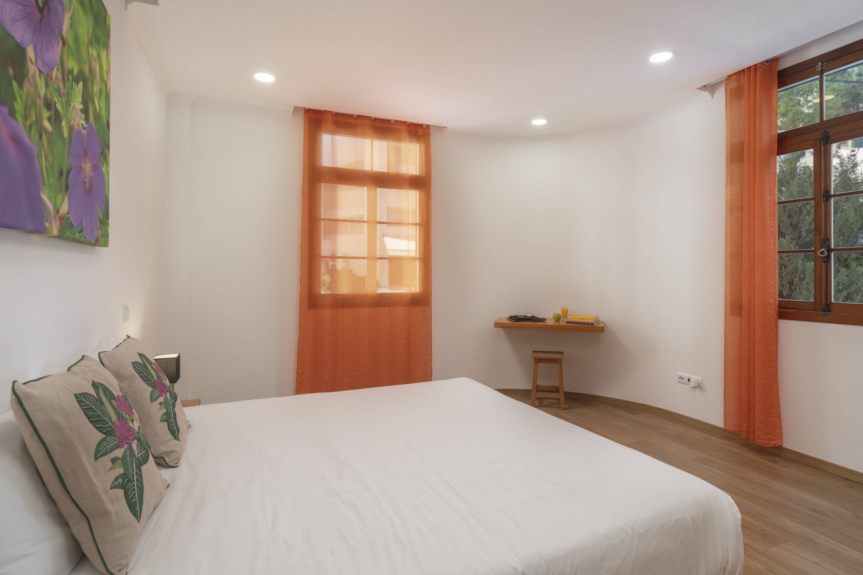 Une chambre avec un grand lit, un bureau avec une chaise et une fenêtre avec des rideaux.