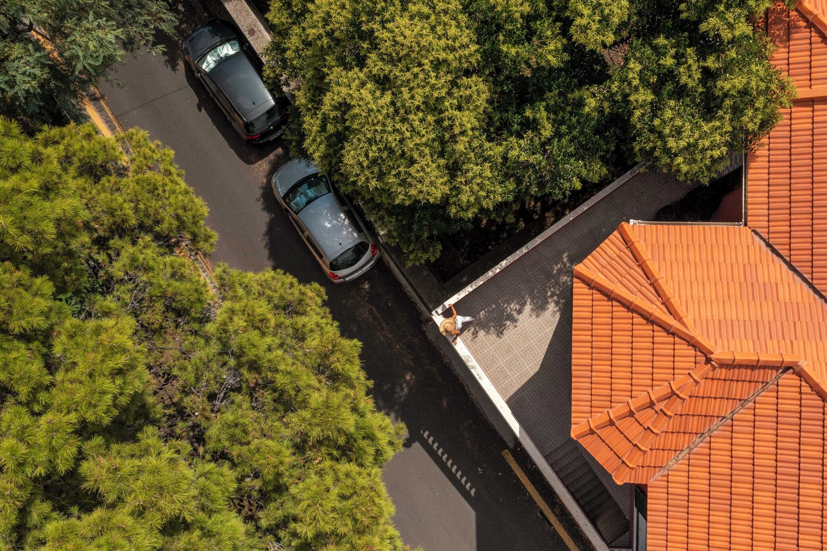 Vista aerea di una strada con auto parcheggiate e alberi.