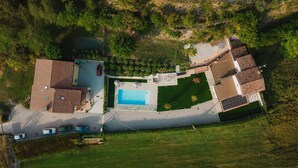 Vista aèria d'una propietat residencial amb piscina, diversos cotxes i jardí.