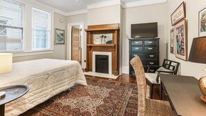 Un dormitorio con cama, chimenea, televisor y zona de comedor.
