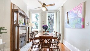 Un comedor con una mesa de madera, sillas, una chimenea y un ventilador de techo.
