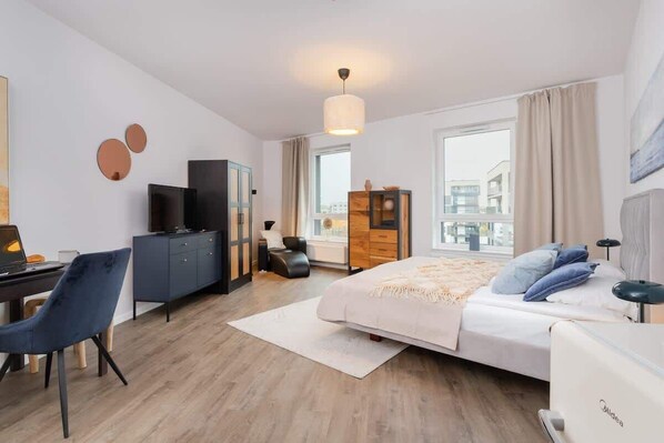 A modern hotel room with a bed, desk, and wardrobe.