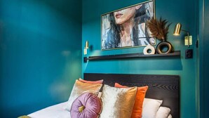 A bed with multiple pillows, a headboard, a wall-mounted shelf with decorative items, and a framed artwork above the bed. - Cozy Studio in the Center | Balcony | Close to Train Station (Katowice)