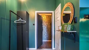 A hallway with a wooden floor, a black metal hanger rack, a white door, and a mirror with a circular frame. - Cozy Studio in the Center | Balcony | Close to Train Station (Katowice)