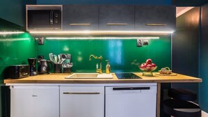 A modern kitchen with a green backsplash, a built-in microwave, a sink, and a dishwasher.
