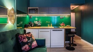 A compact kitchen with a green backsplash, a white dishwasher, and a small island with bar stools.