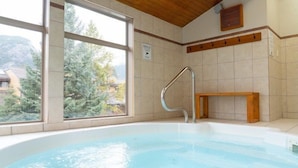 Une salle de spa dotée d’une grande fenêtre, d’un banc en bois et d’une main courante en métal.