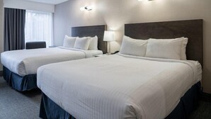 Une chambre d’hôtel avec deux lits, un bureau et une chaise.
