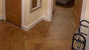 Una habitación con puerta de madera, un espejo, una cama con ropa de cama azul y un reloj en la pared.