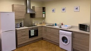 Una cocina compacta equipada con refrigerador, horno, microondas y lavadora.