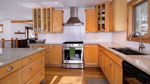 Une cuisine avec des meubles en bois, une cuisinière en acier inoxydable et une fenêtre donnant sur un beau paysage.