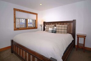 A bedroom with a wooden bed, a window with a view of trees, and a bedside table. - Mountain Vista, 4BD/3BA House, Pet Friendly! (Skyland & Surrounding Areas)