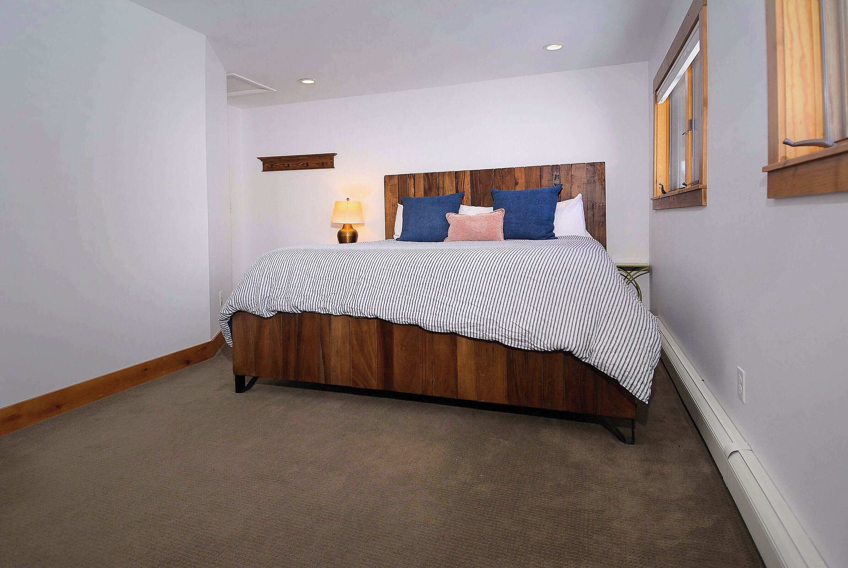 Une chambre à coucher avec une tête de lit en bois, une couvre-lit à rayures et une lampe de chevet.