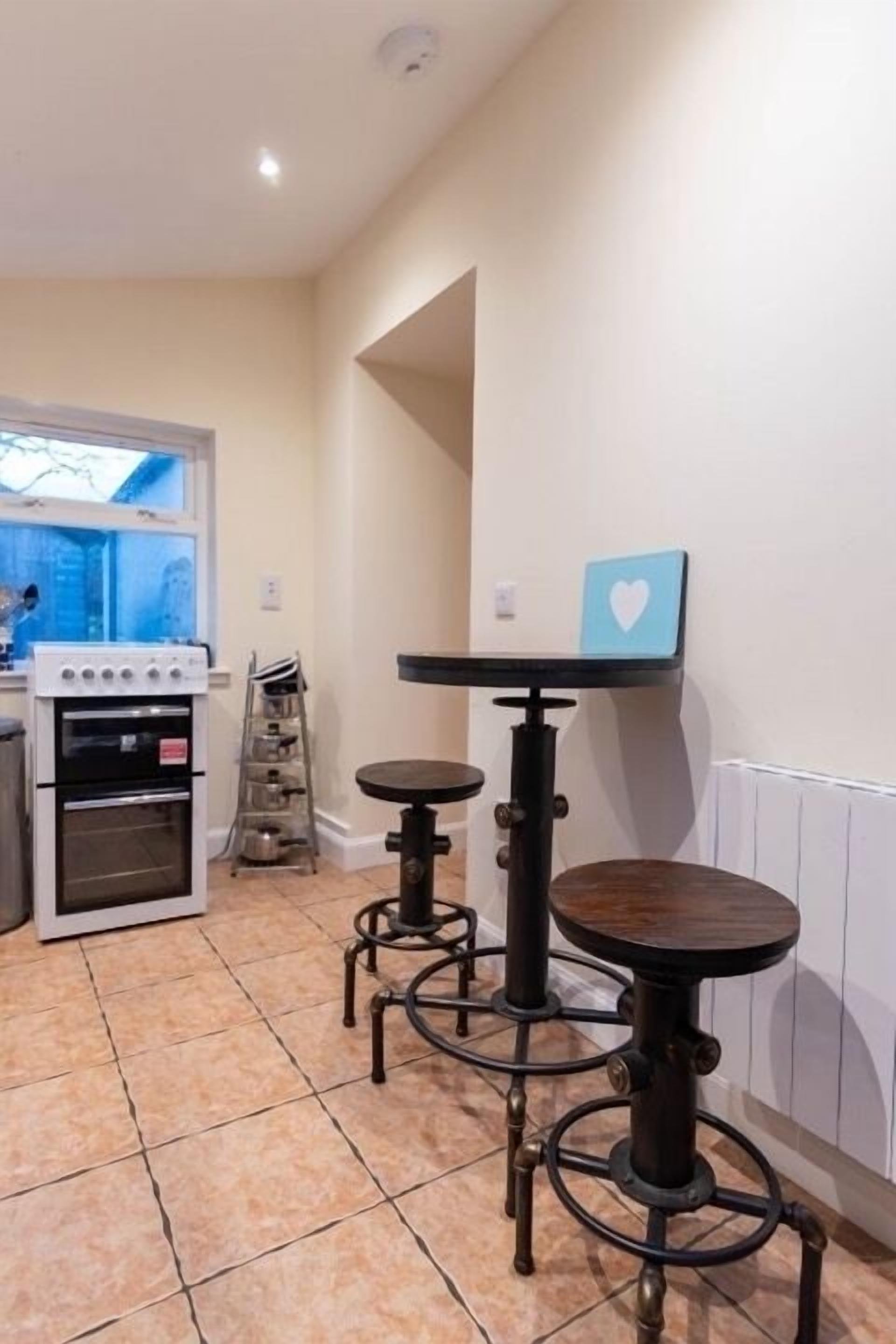 Une cuisine équipée d’une cuisinière, d’un four et d’une petite table avec des tabourets.