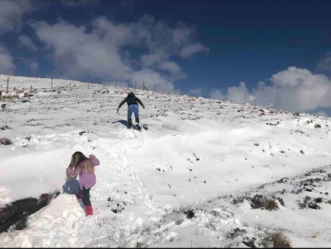 Un paysage enneigé avec une personne au loin et une autre au premier plan.