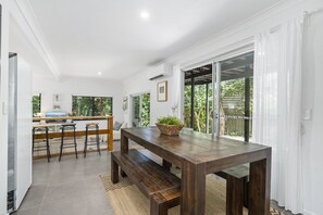 A modern kitchen with a wooden table, bar stools, and a large window.
