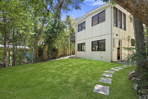 A modern two-story house with a well-maintained lawn and a stone pathway leading to the entrance.