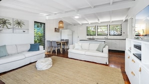 Una sala de estar moderna con sofás blancos, un comedor y una cocina.