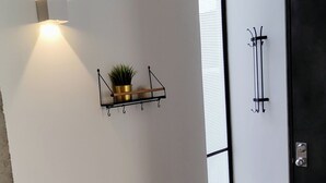Een hal met een lamp, een plant op een plank en een kapstok.