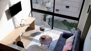 Een moderne woonkamer met een bank, salontafel en een aan de muur bevestigde televisie.